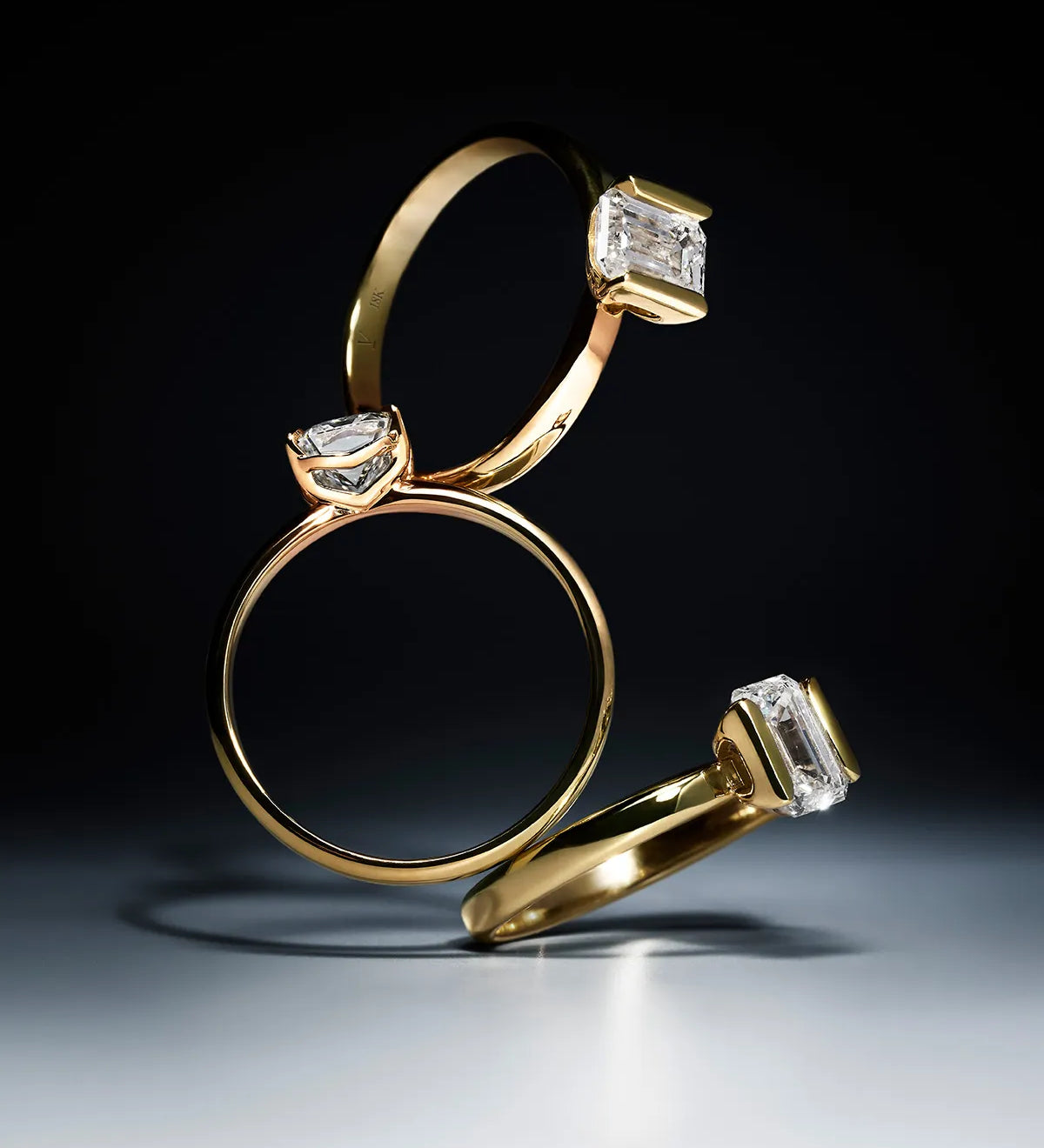 Three gold rings with lab-grown diamond accents on a dark background