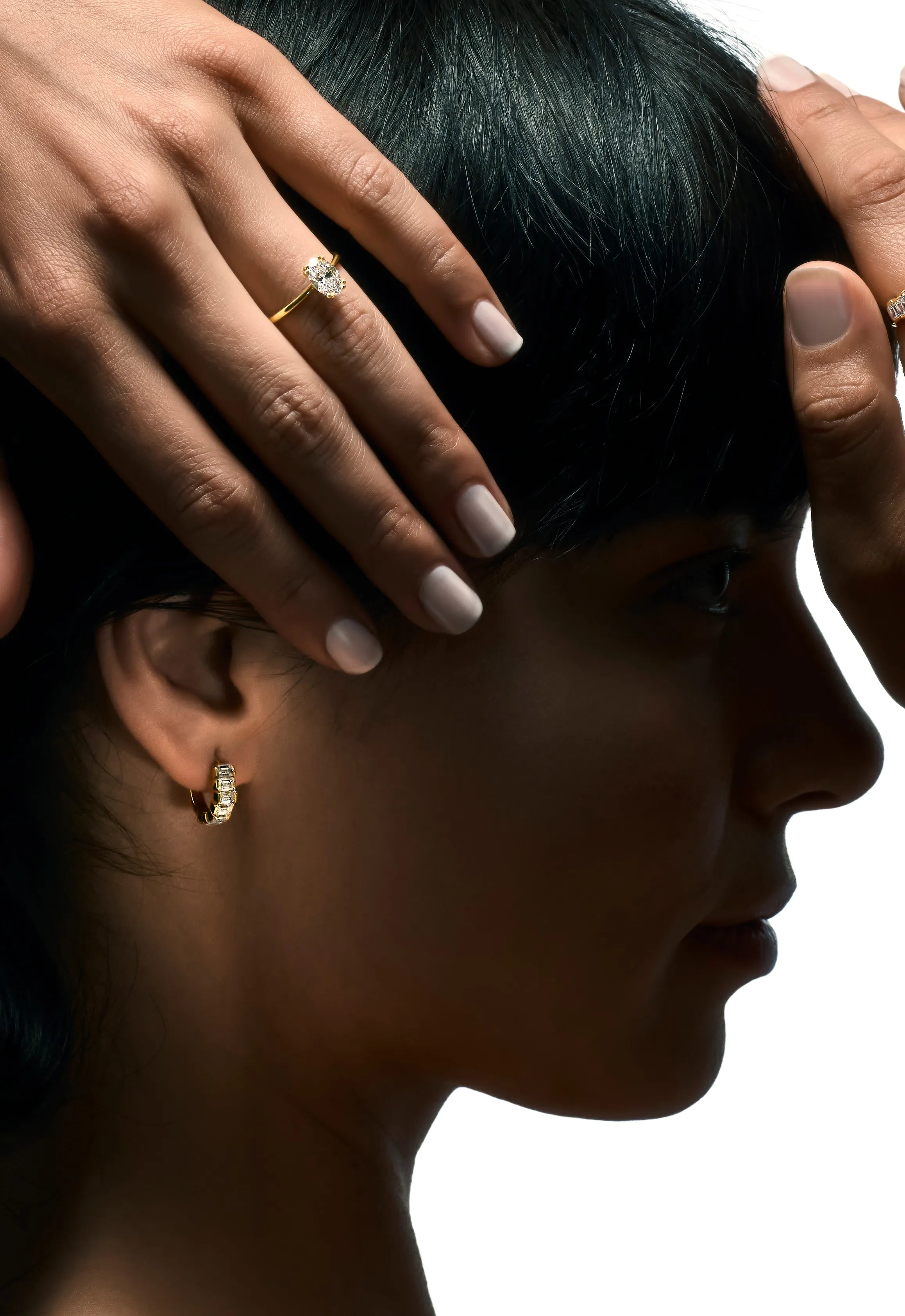 Silhouette of a woman with hands on her head, wearing golden Delve jewelllery with lab-grown diamonds.